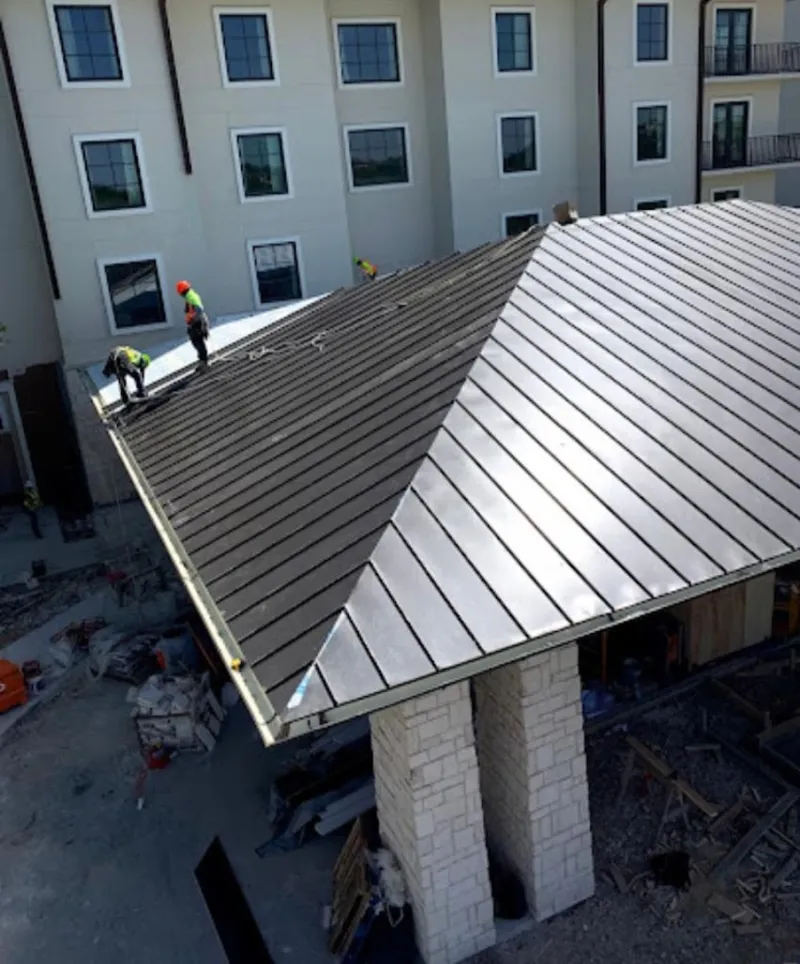 Crew installing standing seam metal roof panels on a commercial project in West Chester